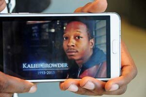 Kamal Browder holding his phone with an image of his late brother, Kalief Browder.